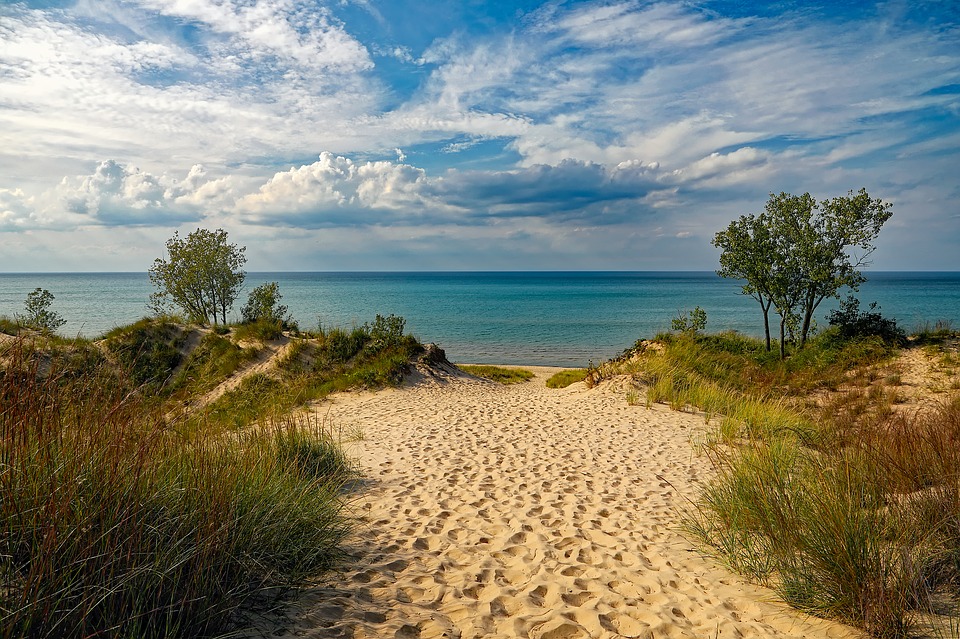 A path through the sand and between dunes to the beach.